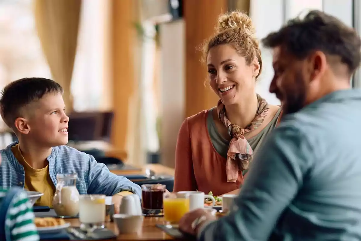 Family sitting at a restaurant table enjoying breakfast together and chatting cheerfully Family sitting at a restaurant table enjoying breakfast together and chatting cheerfully