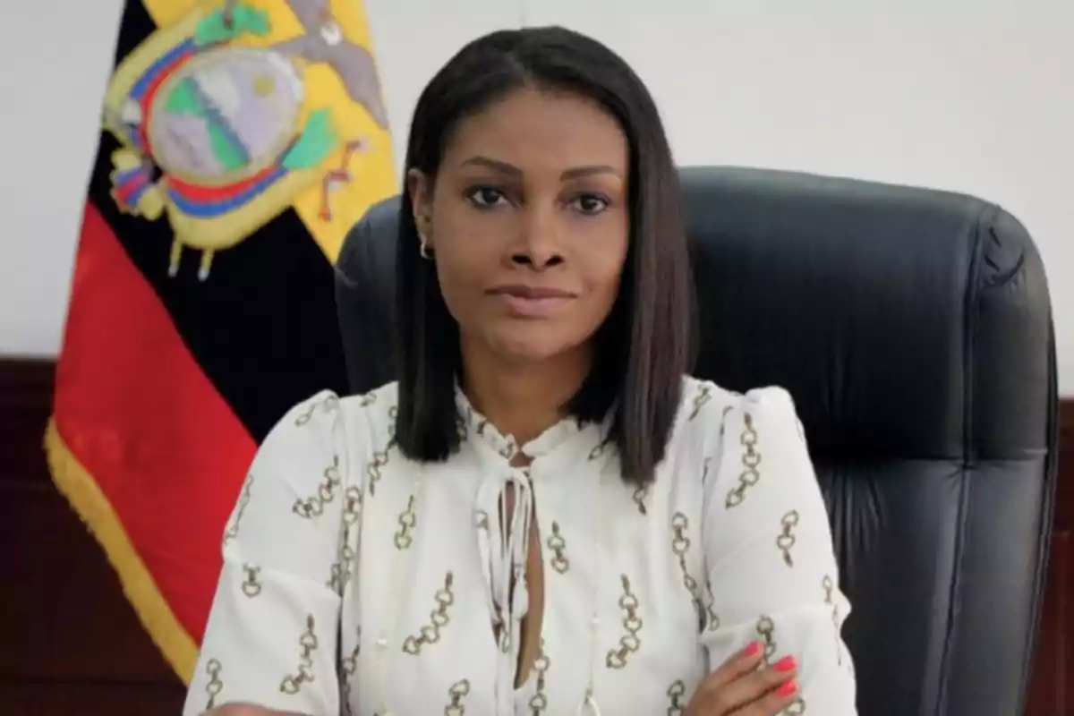 Una persona sentada en una silla de oficina con una bandera de Ecuador al fondo. Una persona sentada en una silla de oficina con una bandera de Ecuador al fondo.