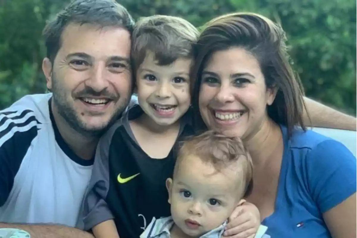 A smiling family posing outdoors.