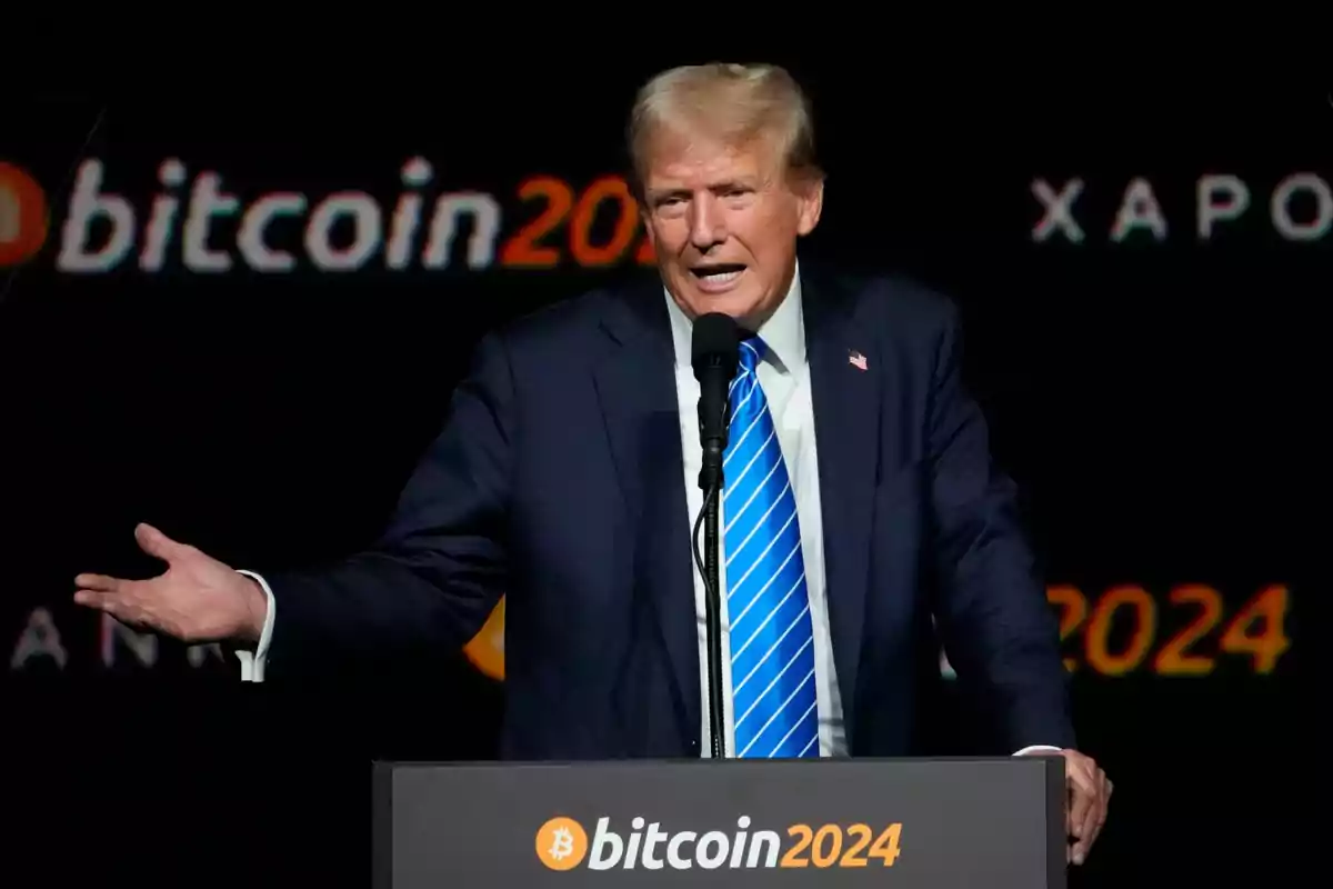 A man in a blue suit and a blue striped tie speaks at a podium with the Bitcoin 2024 logo on a dark background. A man in a blue suit and a blue striped tie speaks at a podium with the Bitcoin 2024 logo on a dark background.