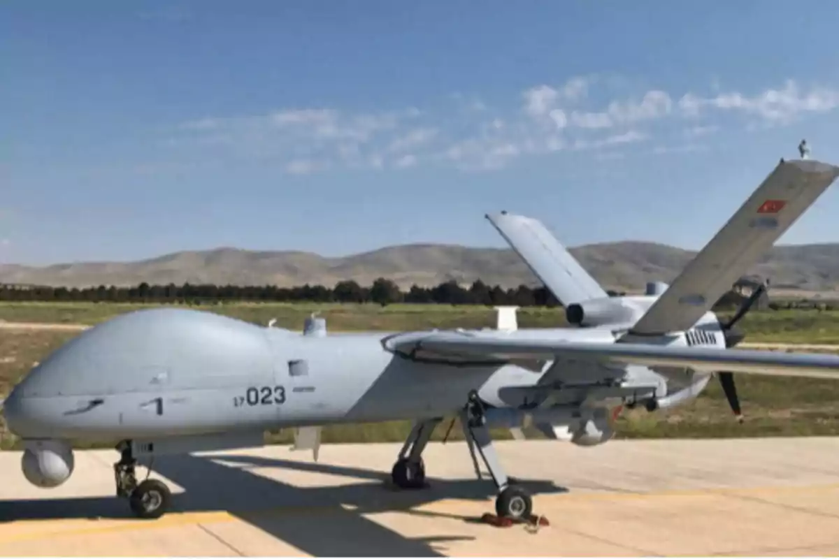 Un dron militar estacionado en una pista de aterrizaje con un paisaje montañoso al fondo. Un dron militar estacionado en una pista de aterrizaje con un paisaje montañoso al fondo.