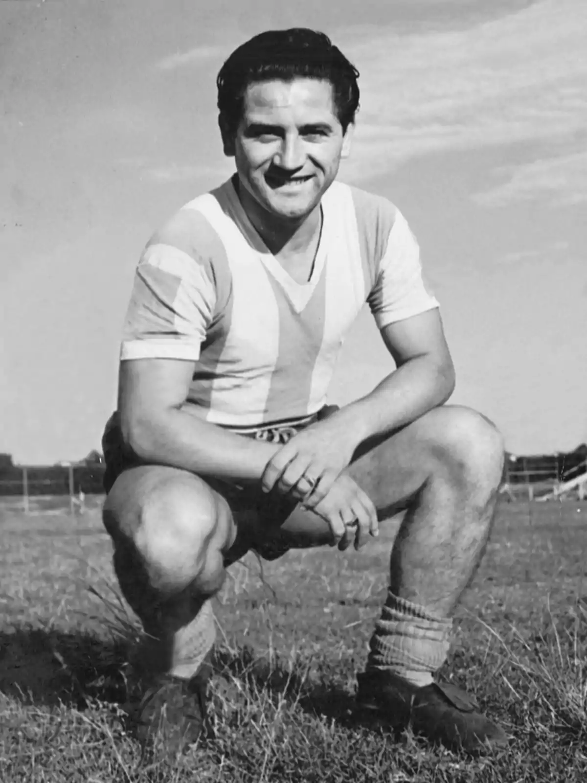 Un jugador de fútbol en uniforme a rayas posando en cuclillas sobre el césped. Un jugador de fútbol en uniforme a rayas posando en cuclillas sobre el césped.