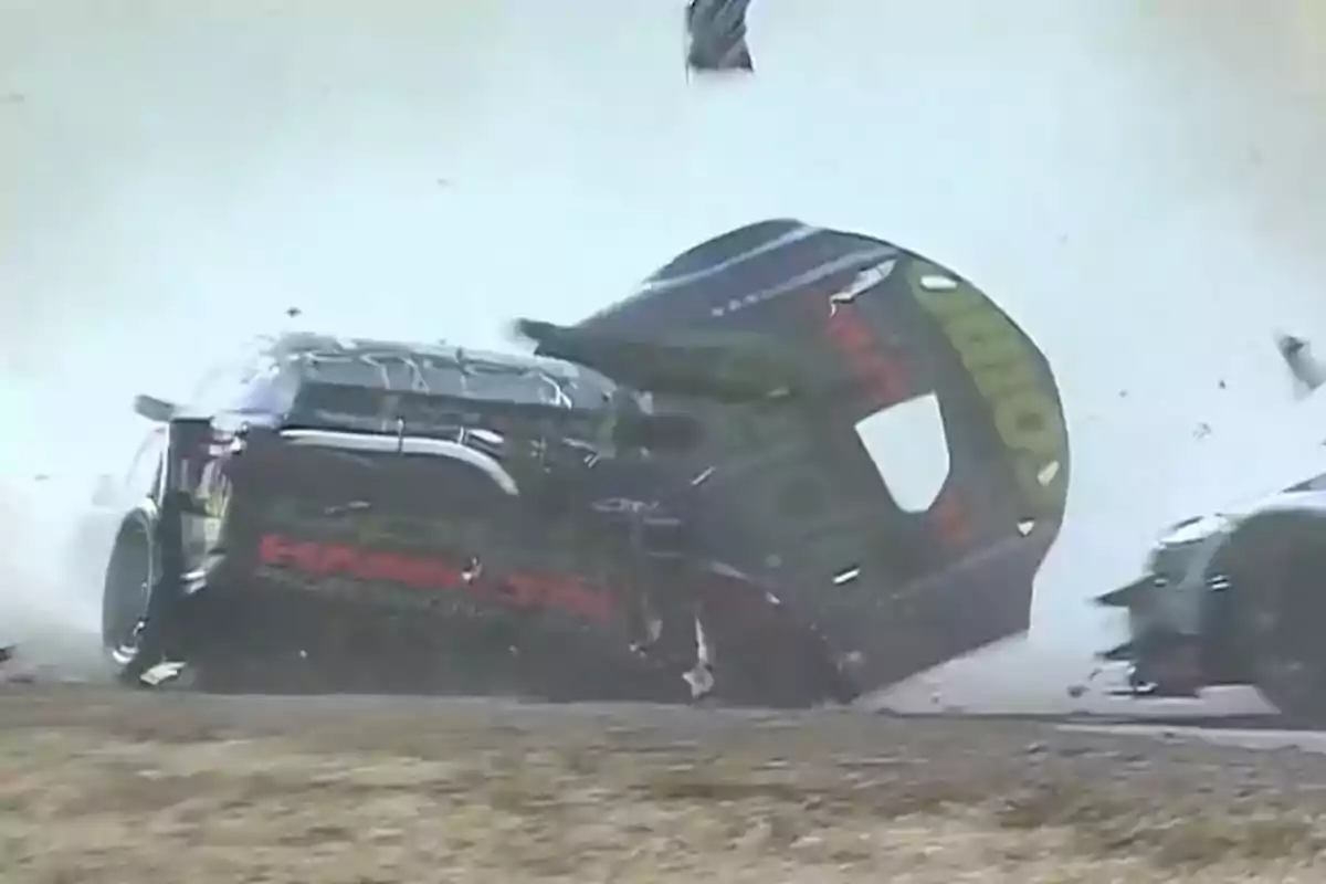 A race car crashing on the track with parts flying and smoke around.