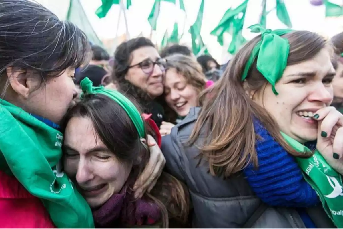 Un grupo de personas con pañuelos verdes muestra emociones intensas en una manifestación.