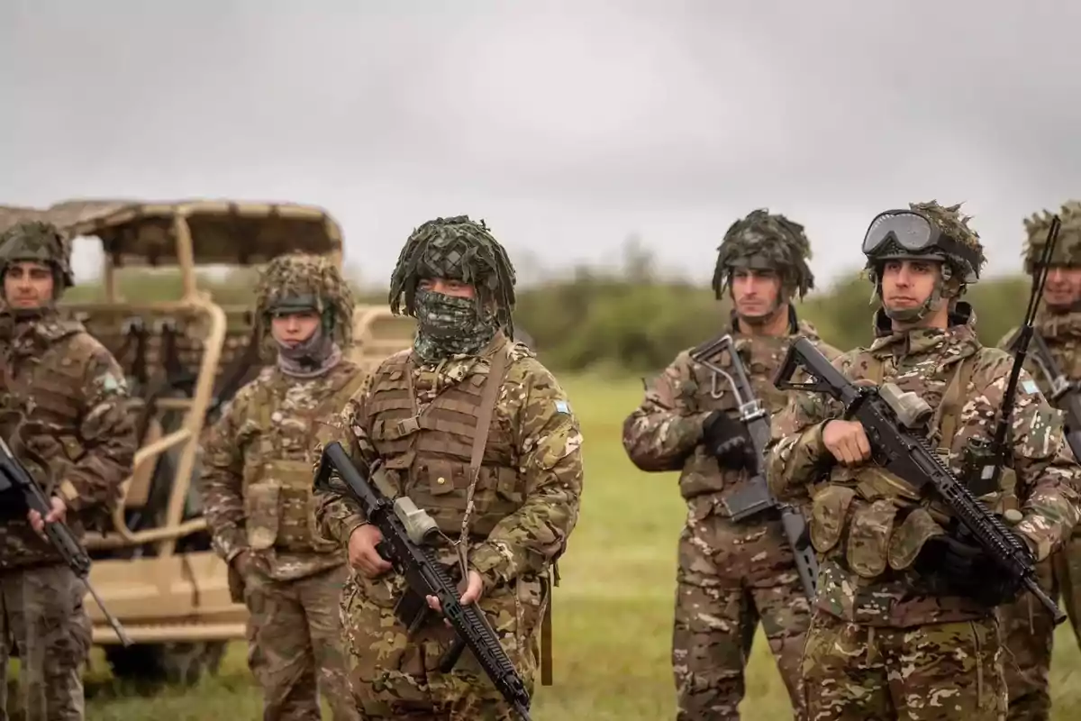 Un grupo de soldados en uniforme de camuflaje con armas en un campo abierto.