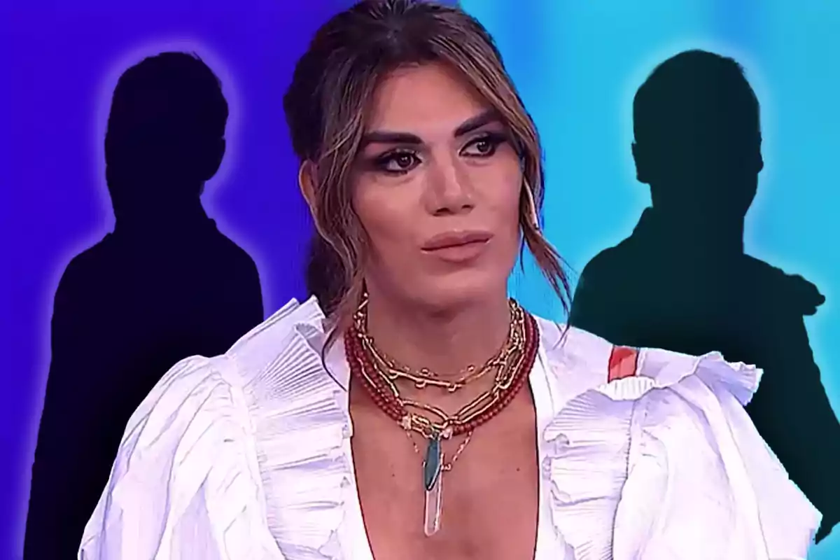 Una persona con cabello oscuro y maquillaje elegante lleva un collar llamativo y una blusa blanca con volantes, mientras que dos siluetas oscuras se destacan en el fondo colorido.