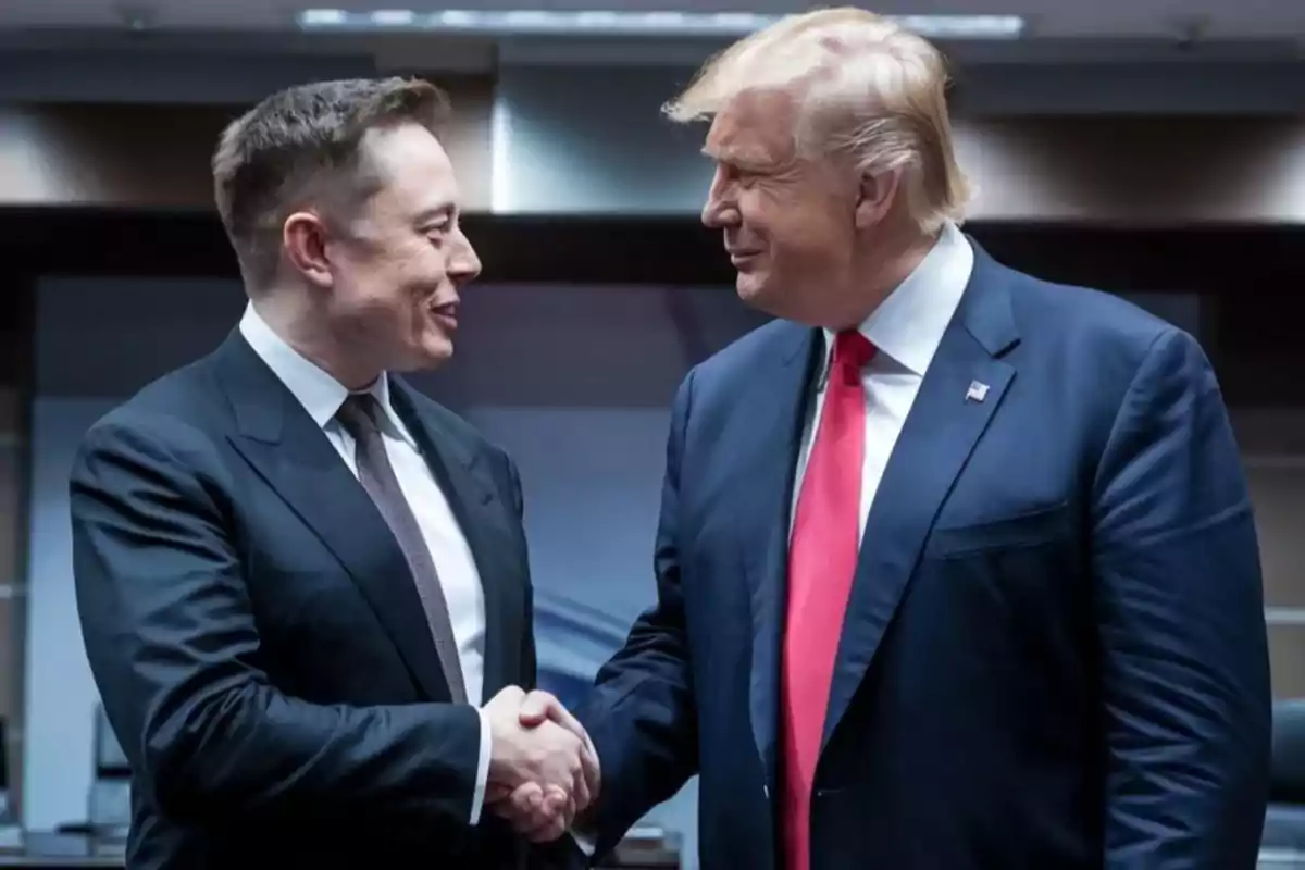 Two men in suits shake hands and smile at each other in a meeting room.