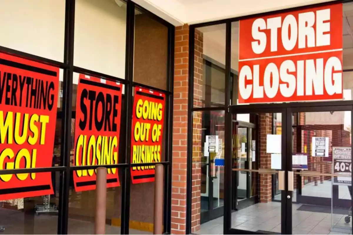 Carteles en una tienda anunciando su cierre y liquidación total.