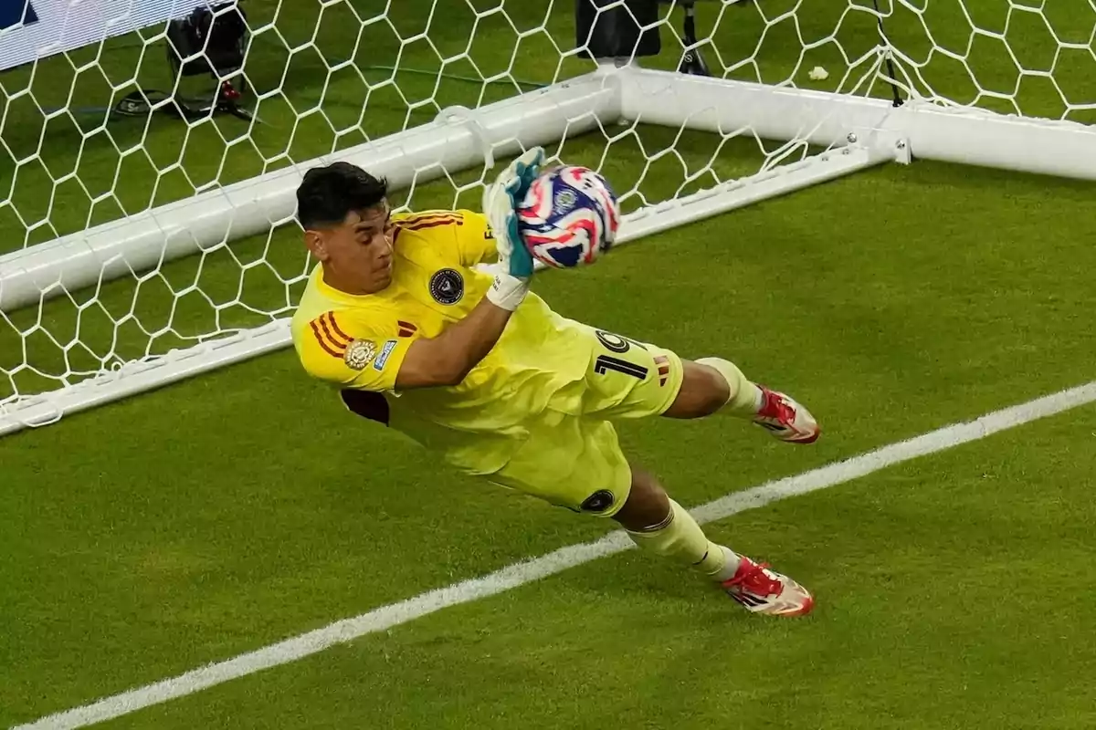 Goalkeeper in a yellow uniform saving a ball during a soccer match in front of the goal Goalkeeper in a yellow uniform saving a ball during a soccer match in front of the goal