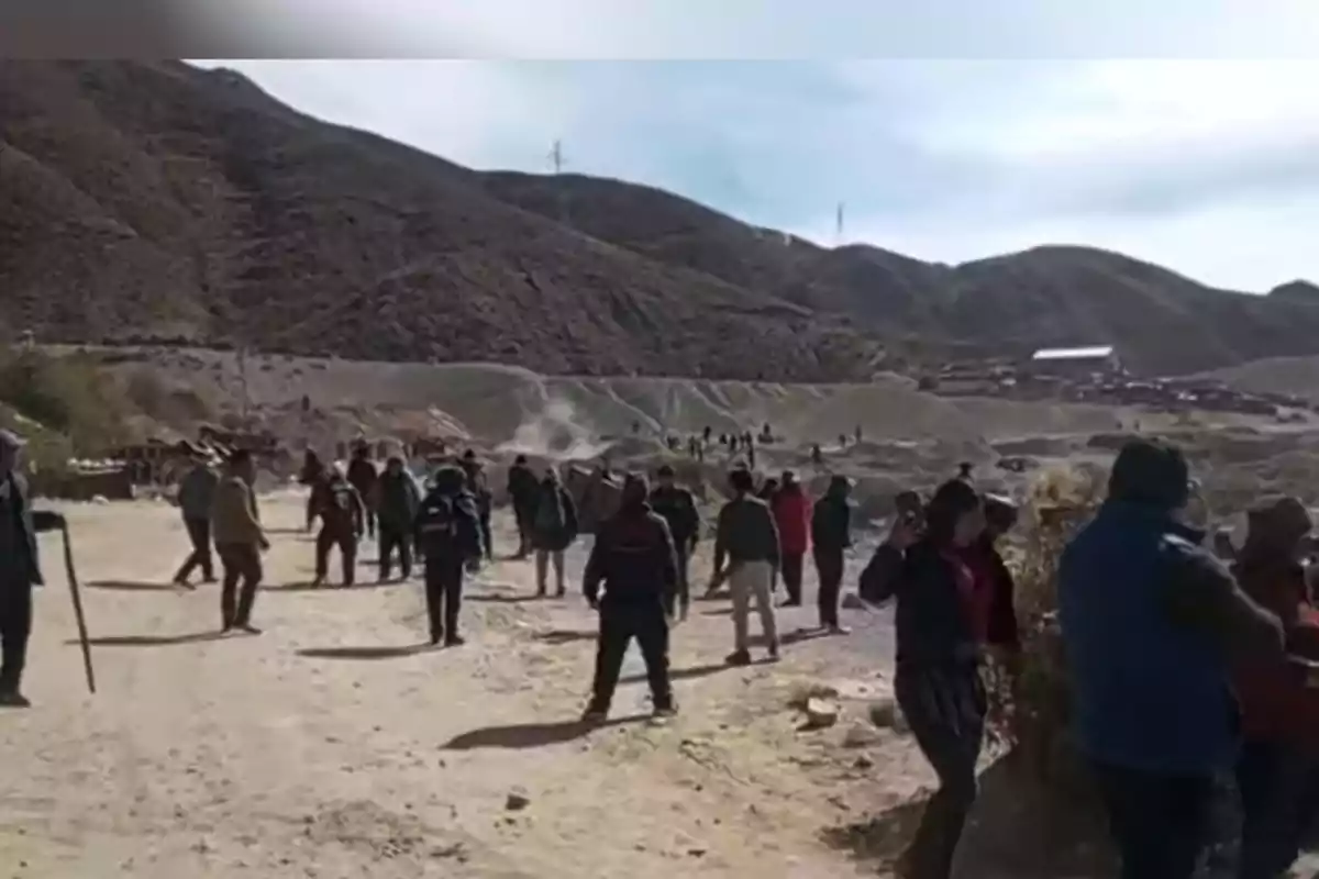 Several people walking and gathered on a dirt path in a mountainous area during the day Several people walking and gathered on a dirt path in a mountainous area during the day