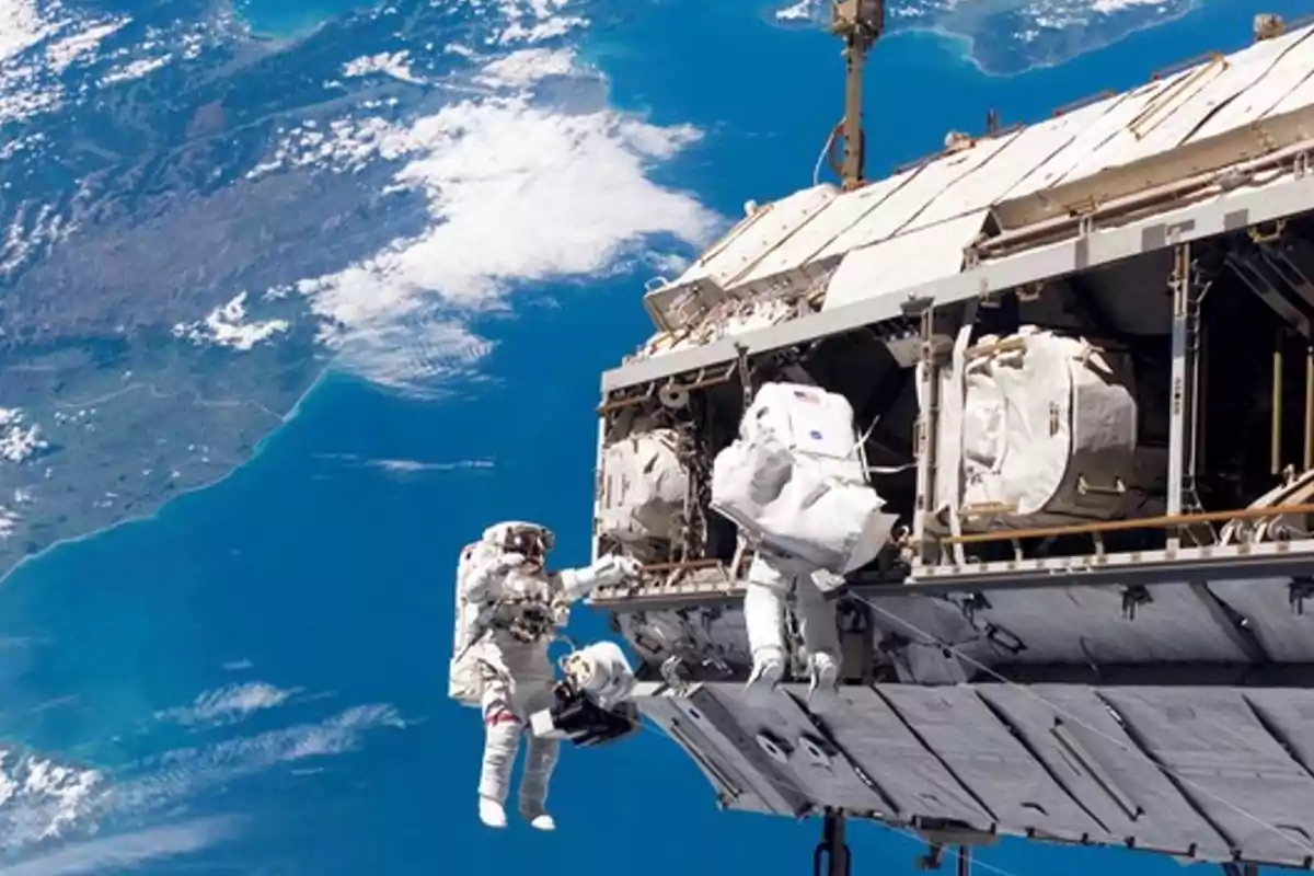 Astronautas realizando una caminata espacial fuera de una estación espacial con la Tierra de fondo.