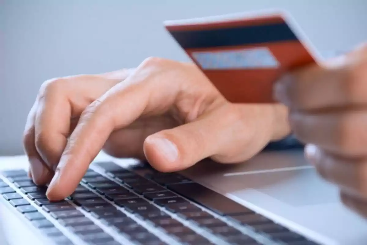 Hands using a computer keyboard while holding a credit card. Hands using a computer keyboard while holding a credit card.
