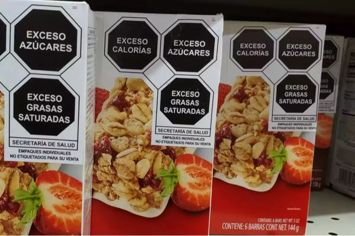 Cajas de barras de cereal en un estante con etiquetas de advertencia que indican exceso de azúcares, calorías y grasas saturadas.