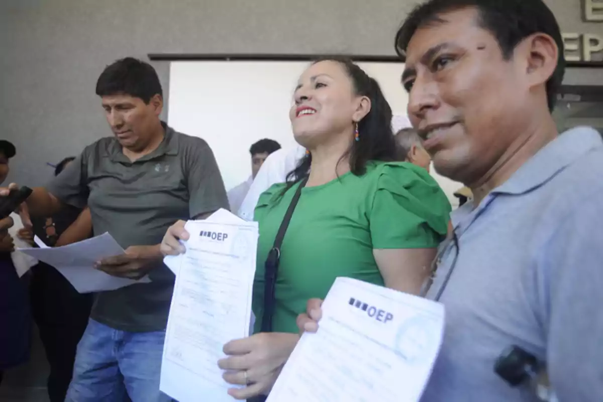 Personas sosteniendo documentos del OEP en un evento público.