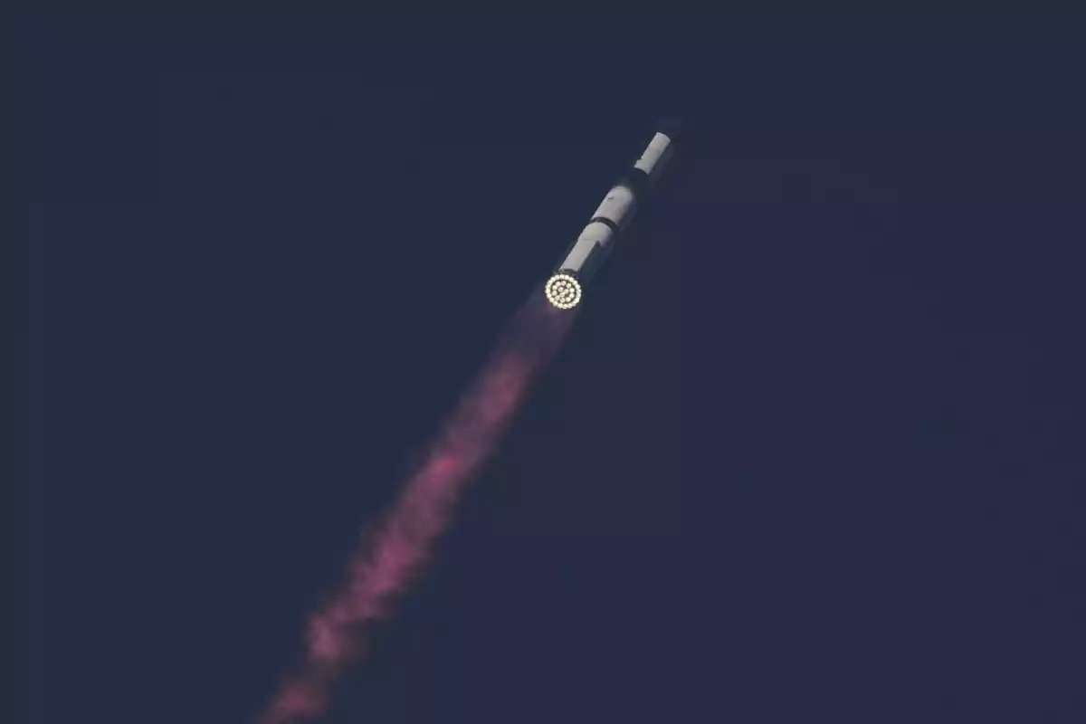 Cohete despegando hacia el espacio dejando una estela rosada en el cielo oscuro Cohete despegando hacia el espacio dejando una estela rosada en el cielo oscuro