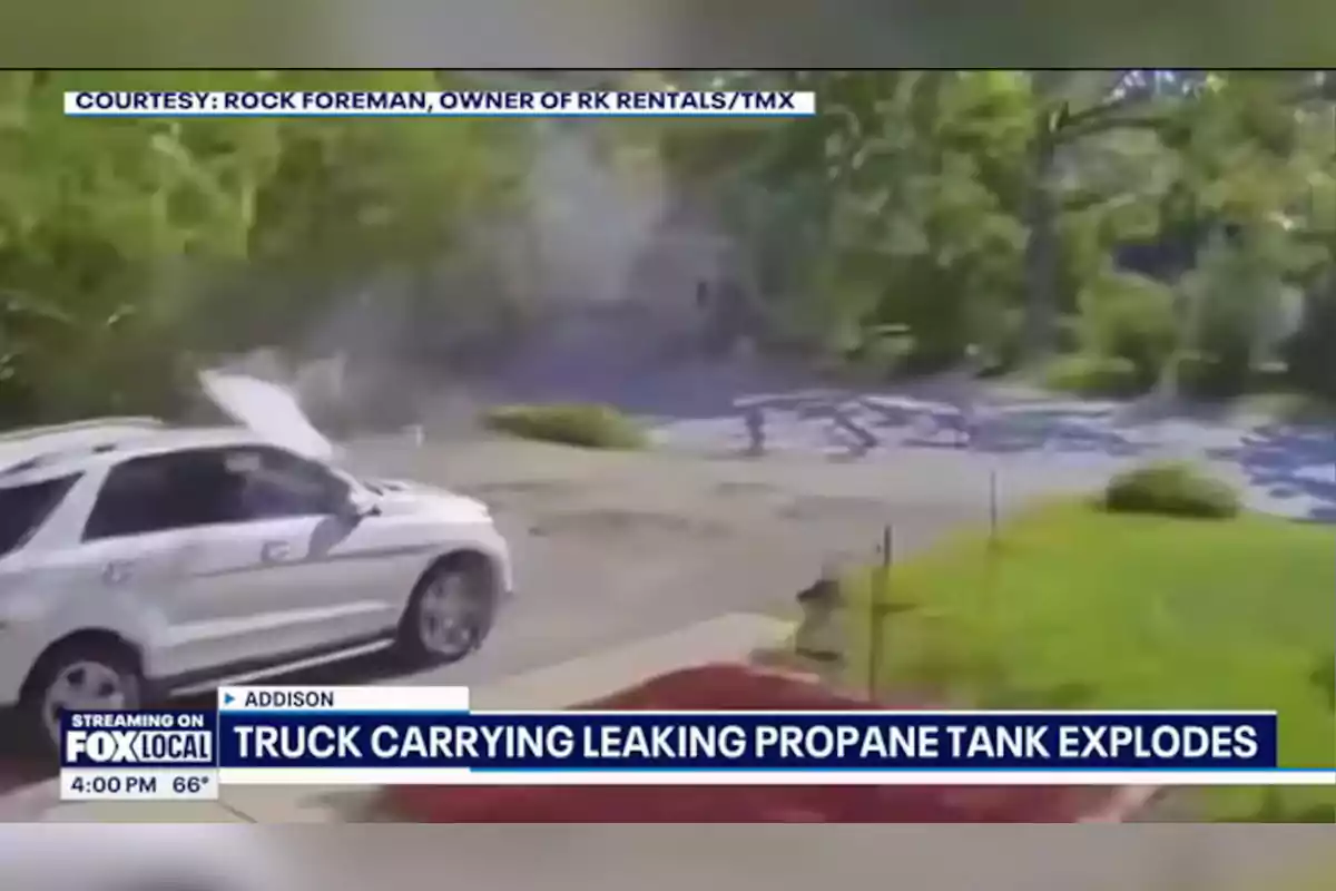 Explosión de un camión con tanque de propano cerca de un auto blanco estacionado en una zona residencial con árboles y césped, imagen tomada de una transmisión de noticias de Fox Local Explosión de un camión con tanque de propano cerca de un auto blanco estacionado en una zona residencial con árboles y césped, imagen tomada de una transmisión de noticias de Fox Local
