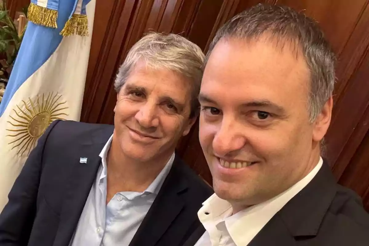 Two people pose for a selfie in front of an Argentine flag.