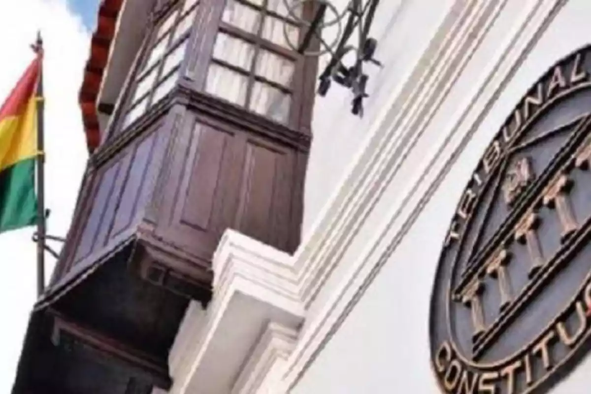 Fachada de un edificio con un balcón de madera, una bandera tricolor y un escudo que dice Tribunal Constitucional Fachada de un edificio con un balcón de madera, una bandera tricolor y un escudo que dice Tribunal Constitucional