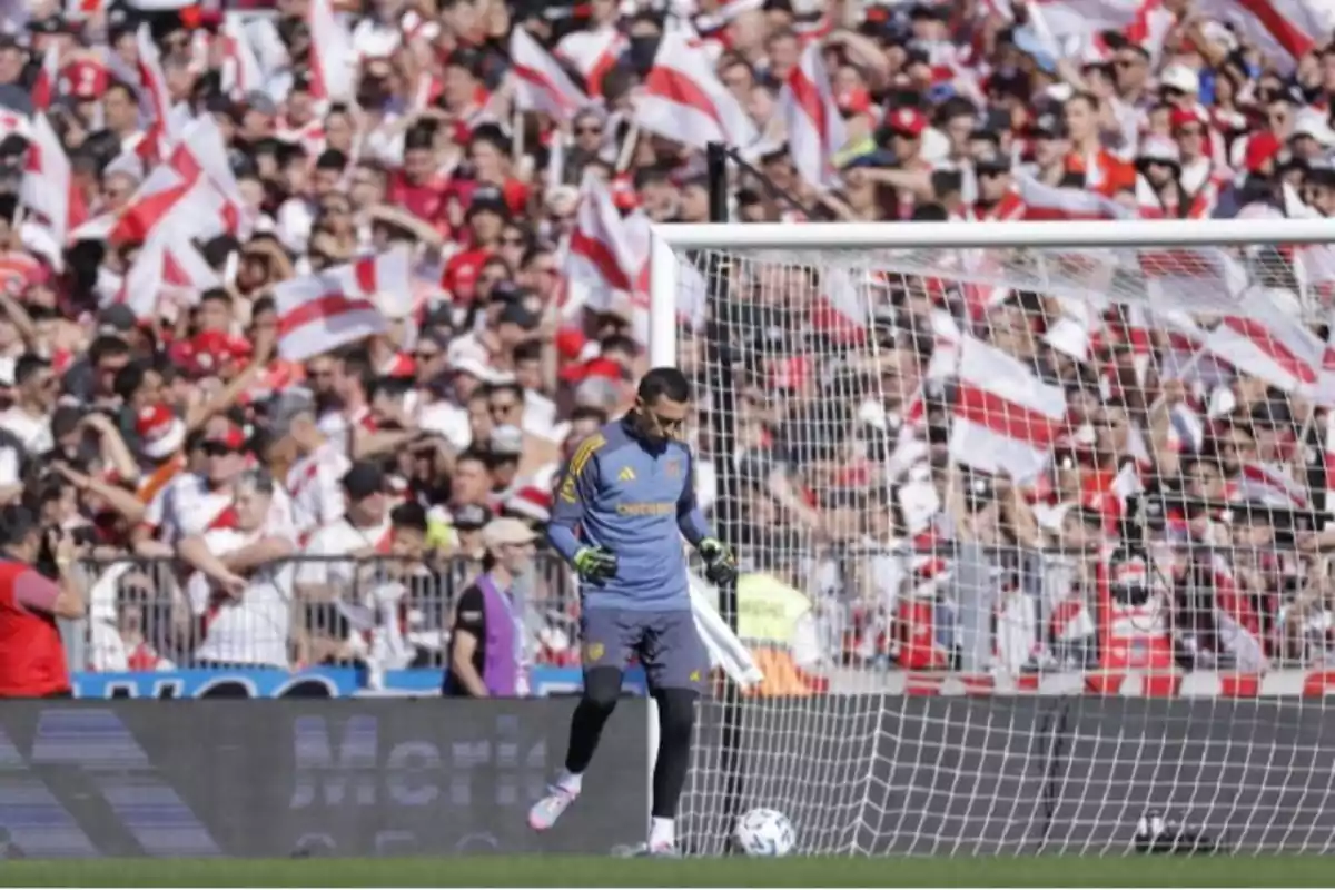 Un arquero de fútbol en el campo con una multitud de aficionados en el fondo ondeando banderas. Un arquero de fútbol en el campo con una multitud de aficionados en el fondo ondeando banderas.