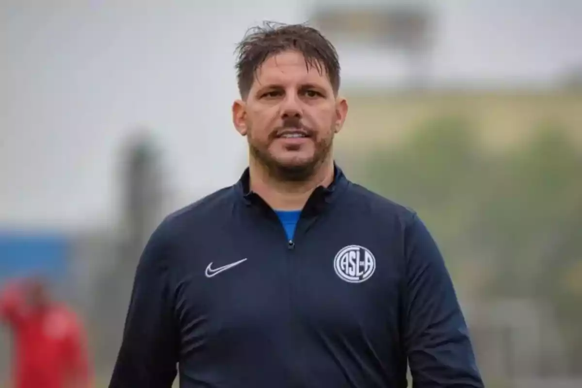 Man wearing a navy blue San Lorenzo de Almagro sports jacket in an outdoor setting