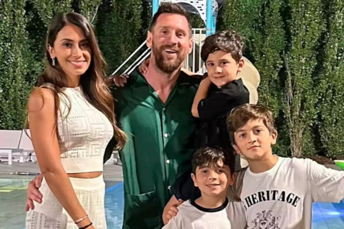 Una familia sonriente posando al aire libre frente a un seto verde. Una familia sonriente posando al aire libre frente a un seto verde.