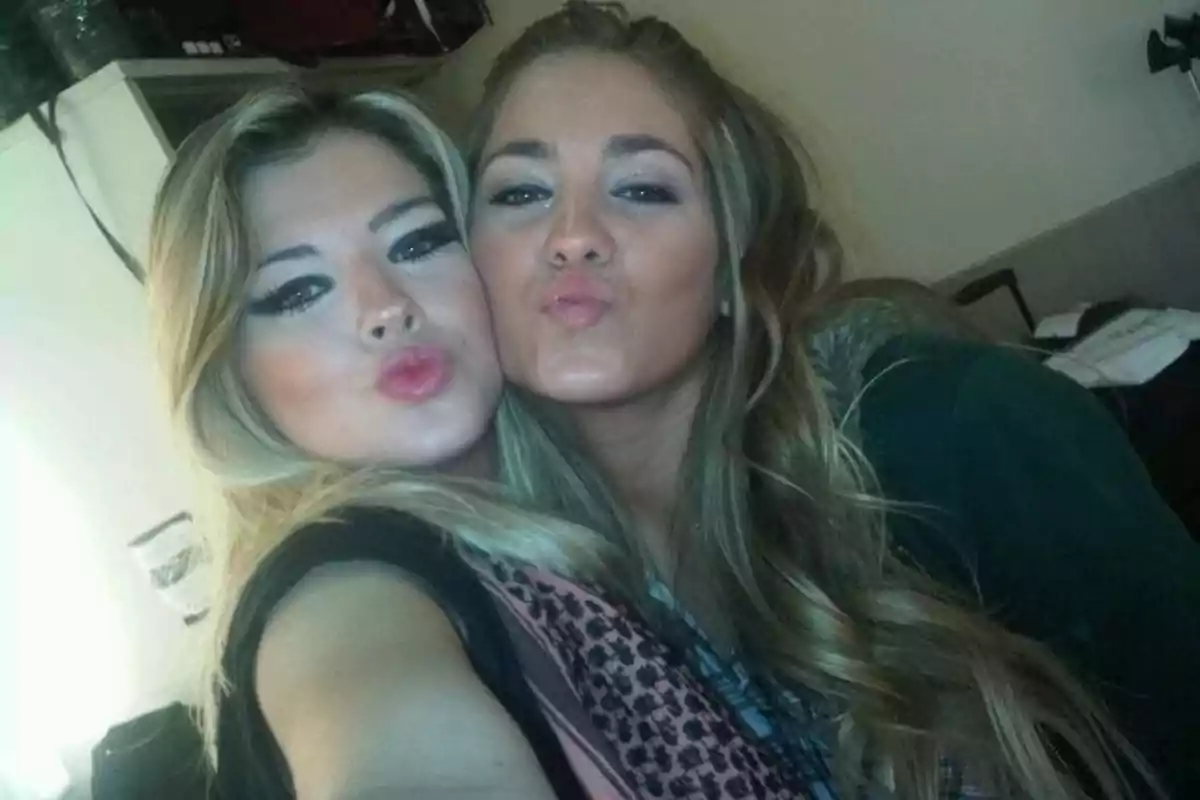 Dos mujeres jóvenes posan para una selfie haciendo un gesto de beso con los labios juntos y el rostro maquillado Dos mujeres jóvenes posan para una selfie haciendo un gesto de beso con los labios juntos y el rostro maquillado