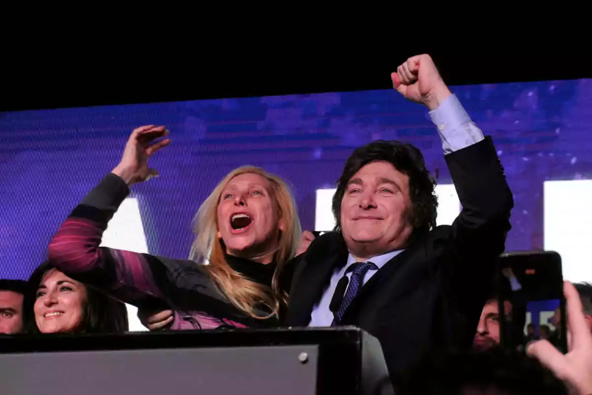 Personas celebrando con los brazos levantados y sonriendo en un evento.