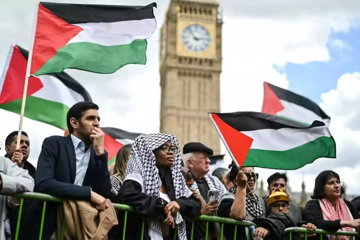 Personas sosteniendo banderas palestinas frente a un edificio emblemático.