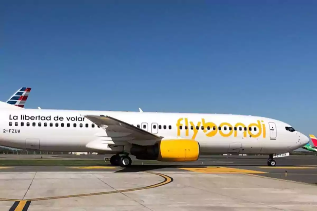 Un avión de la aerolínea Flybondi en la pista de un aeropuerto bajo un cielo despejado.