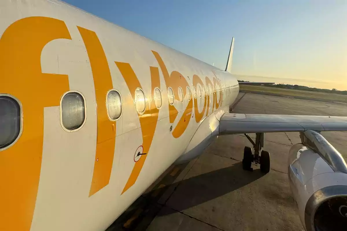 A Flybondi airline plane parked on the runway of an airport at sunset.