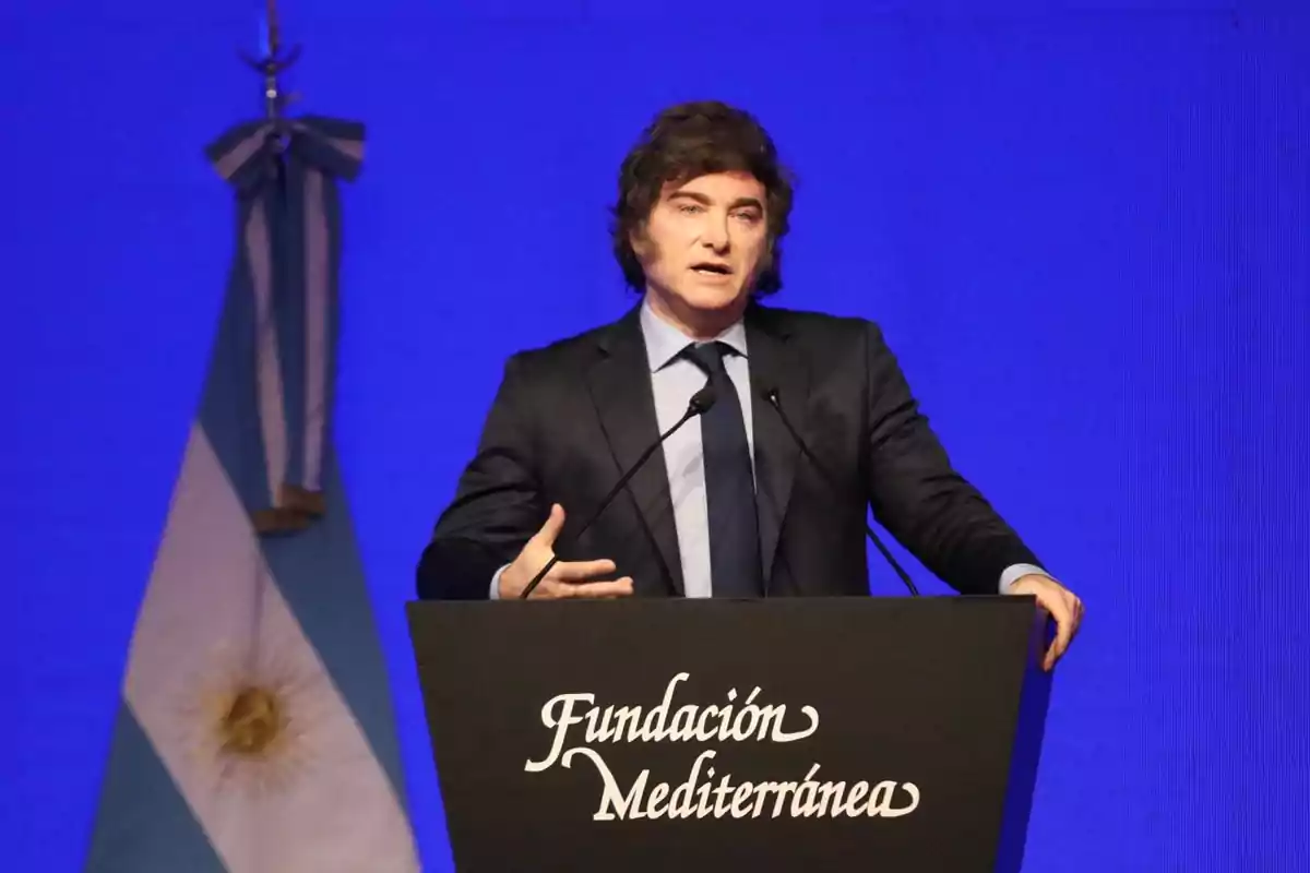 Un hombre hablando en un podio con el texto "Fundación Mediterránea" y una bandera argentina de fondo.