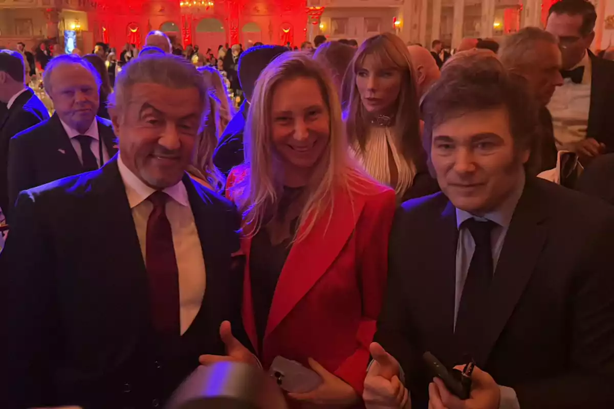 Un grupo de personas posando en un evento elegante con iluminación roja y azul.