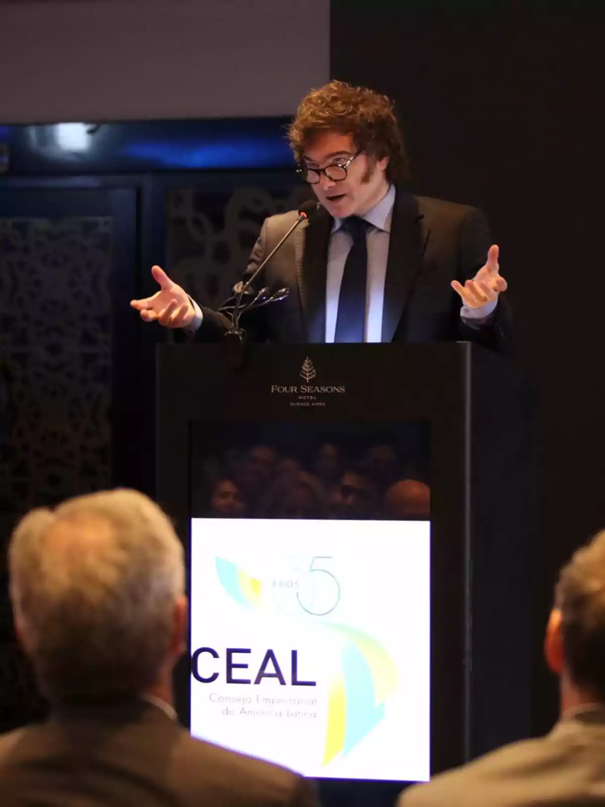 Un hombre con traje y gafas habla en un podio durante un evento del Consejo Empresarial de América Latina en el Hotel Four Seasons.