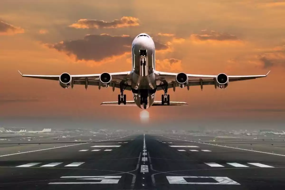 Plane taking off from a runway at sunset with an orange sky in the background Plane taking off from a runway at sunset with an orange sky in the background