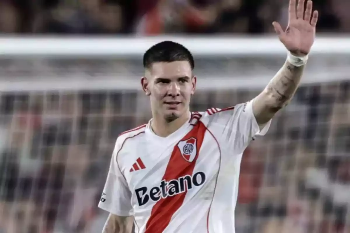 Soccer player in a River Plate uniform waving with his hand raised in a stadium Soccer player in a River Plate uniform waving with his hand raised in a stadium