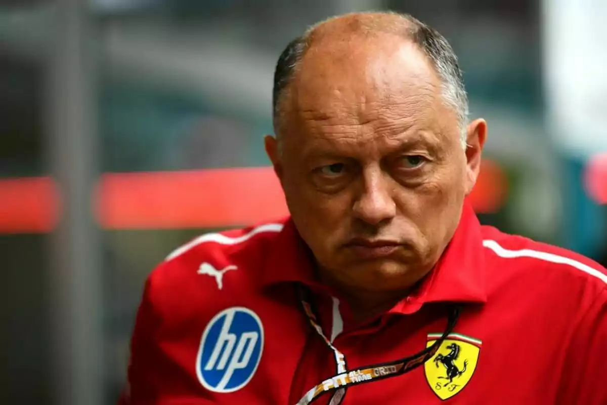 Hombre con expresión seria vistiendo una chaqueta roja con logotipos de HP y Ferrari. Hombre con expresión seria vistiendo una chaqueta roja con logotipos de HP y Ferrari.