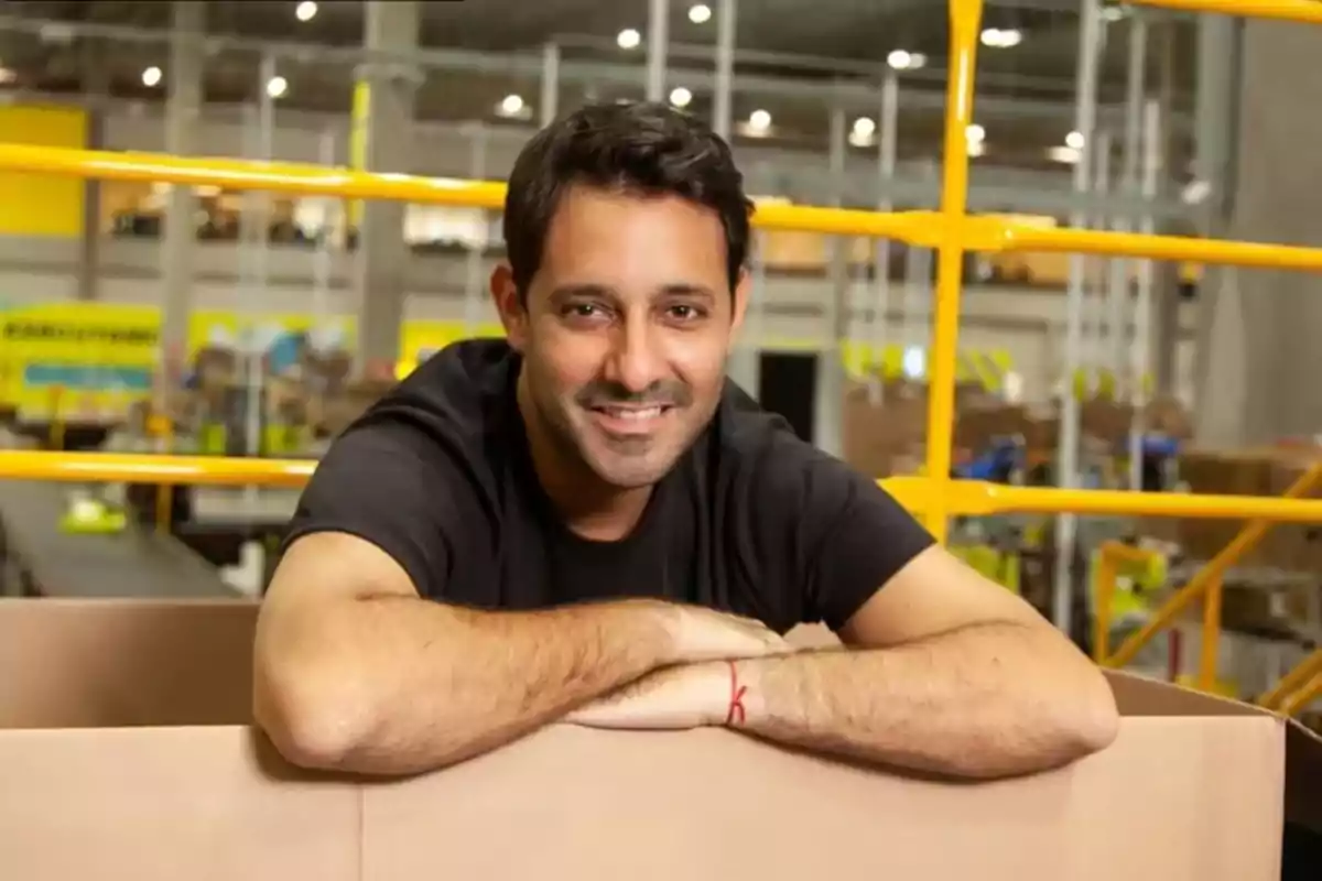 Hombre sonriendo apoyado en una caja en un entorno industrial. Hombre sonriendo apoyado en una caja en un entorno industrial.