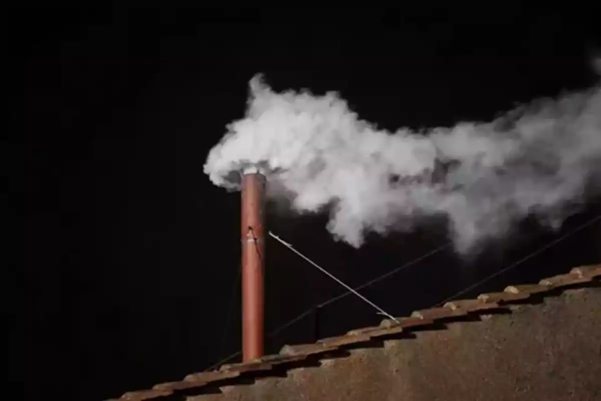 A chimney emitting white smoke at night. A chimney emitting white smoke at night.