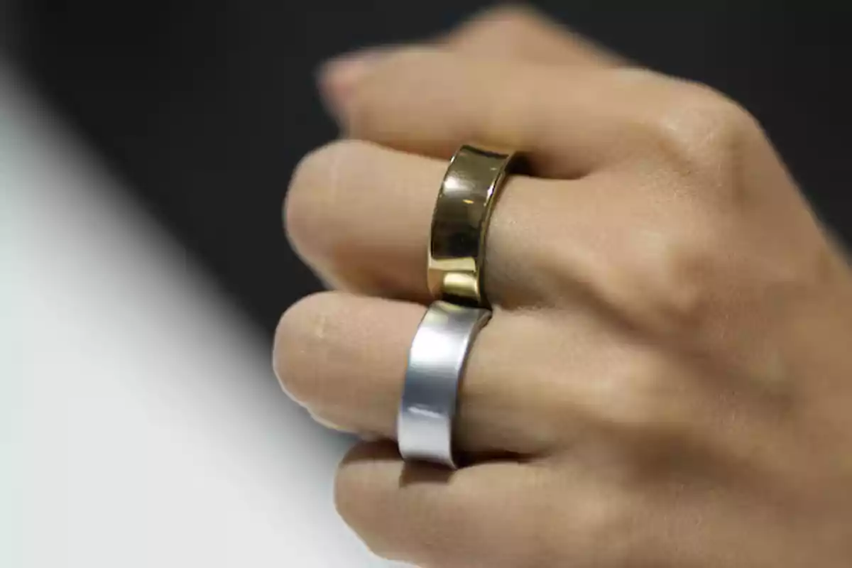 A hand with two metal rings, one gold and one silver, on the fingers. A hand with two metal rings, one gold and one silver, on the fingers.