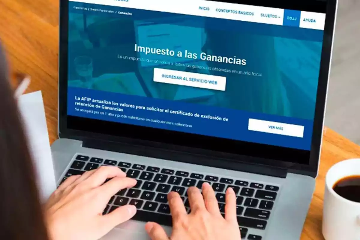 Persona usando una computadora portátil con una página web sobre el impuesto a las ganancias en la pantalla.