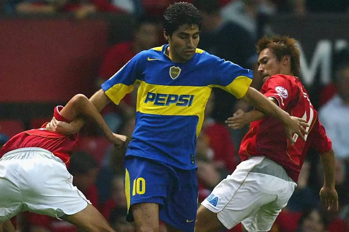 Futbolista de Boca Juniors con camiseta azul y amarilla esquiva a dos rivales vestidos de rojo durante un partido Futbolista de Boca Juniors con camiseta azul y amarilla esquiva a dos rivales vestidos de rojo durante un partido