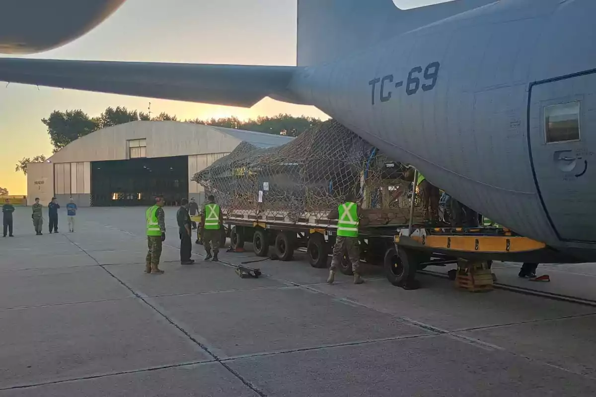 Personal militar cargando un avión de transporte en una base aérea al atardecer.