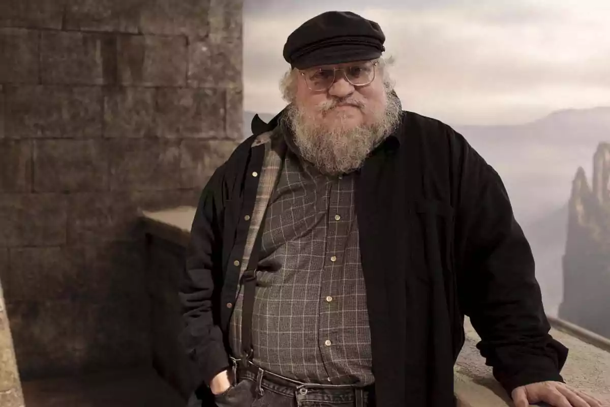 Older man with a beard and glasses, wearing a plaid jersey, suspenders, a black jacket, and a cap, leaning on a stone railing with a mountainous landscape in the background Older man with a beard and glasses, wearing a plaid jersey, suspenders, a black jacket, and a cap, leaning on a stone railing with a mountainous landscape in the background