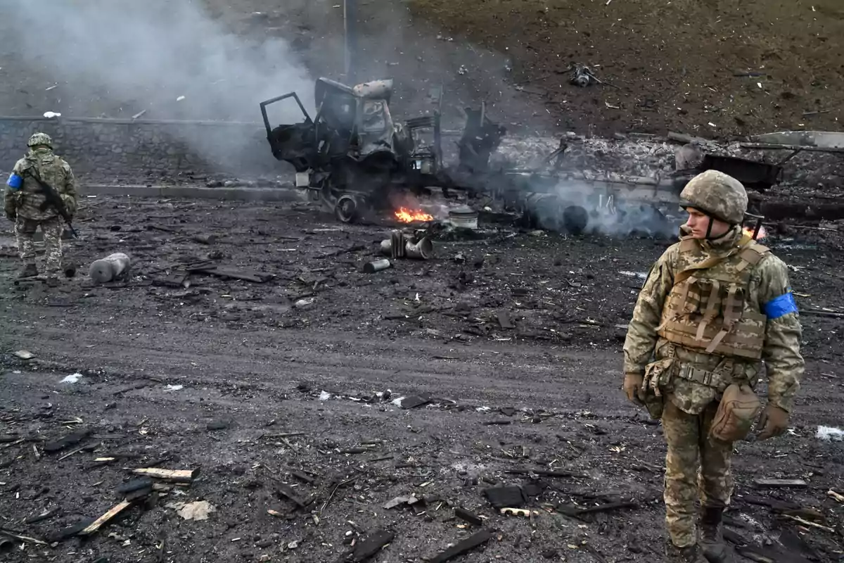Soldados en un campo de batalla con un vehículo destruido y humo en el fondo. Soldados en un campo de batalla con un vehículo destruido y humo en el fondo.
