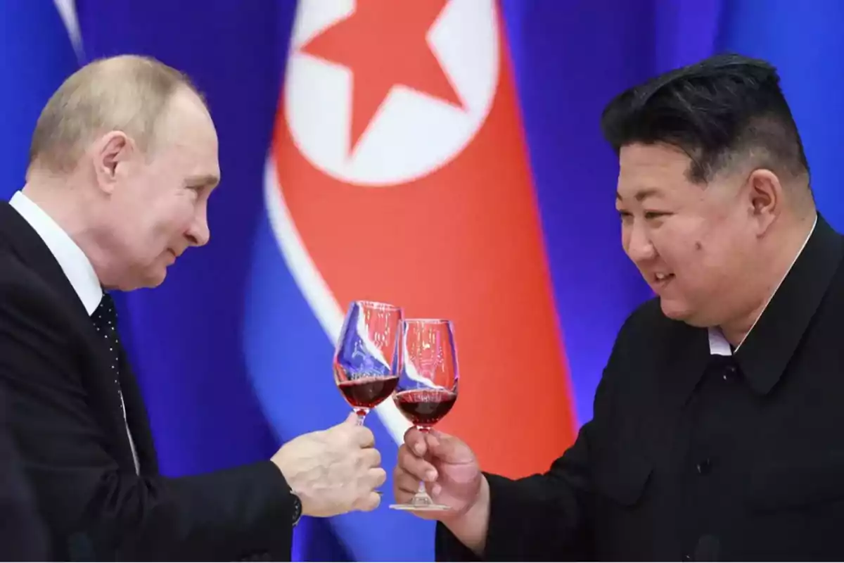 Dos personas brindando con copas de vino frente a una bandera.