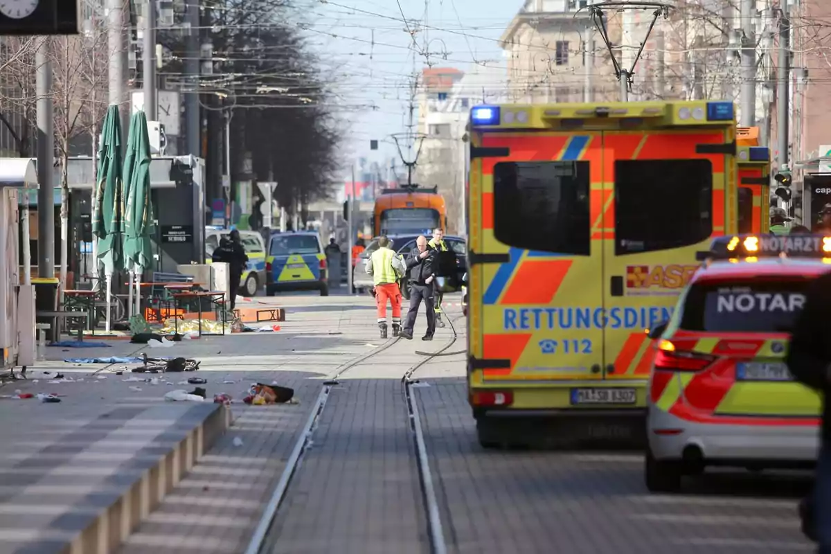 A street with emergency vehicles, including ambulances and police cars, with people working at the scene.