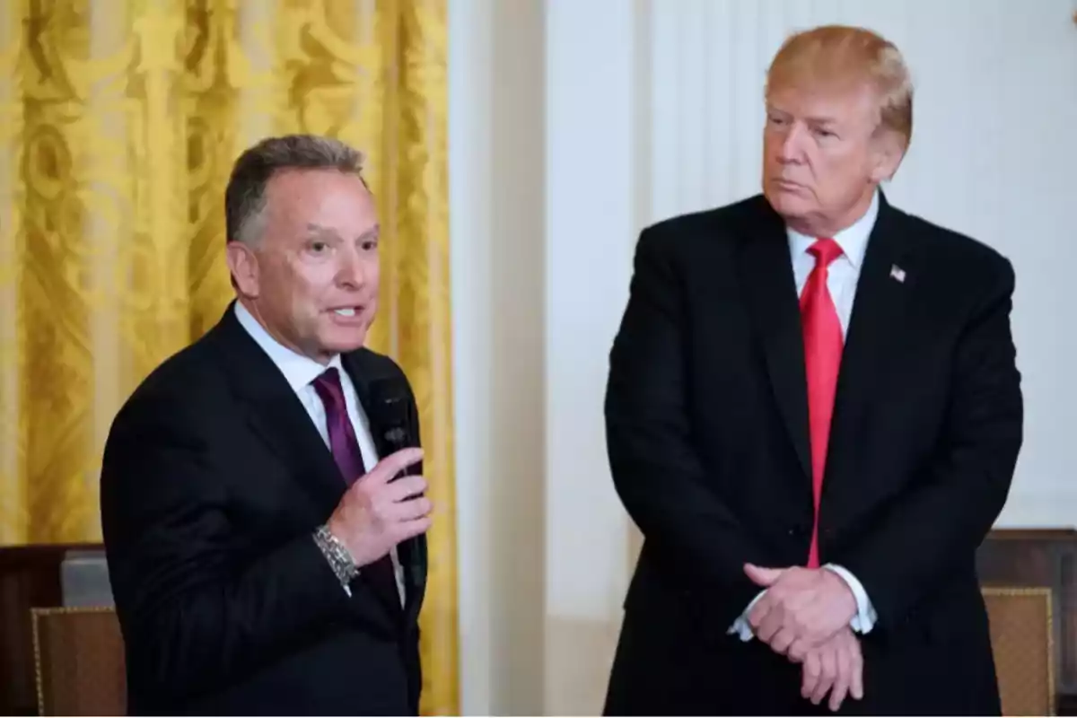 Two men standing, one speaking into a microphone and the other listening, both dressed in formal suits. Two men standing, one speaking into a microphone and the other listening, both dressed in formal suits.