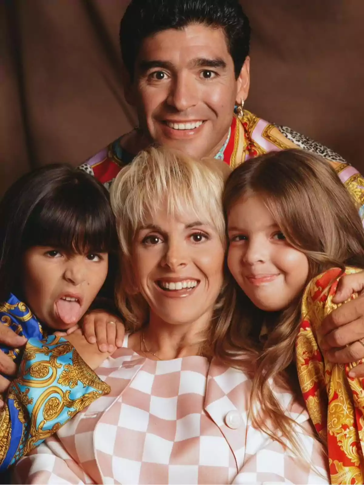 Una familia sonriente posando para una foto con un fondo marrón. Una familia sonriente posando para una foto con un fondo marrón.