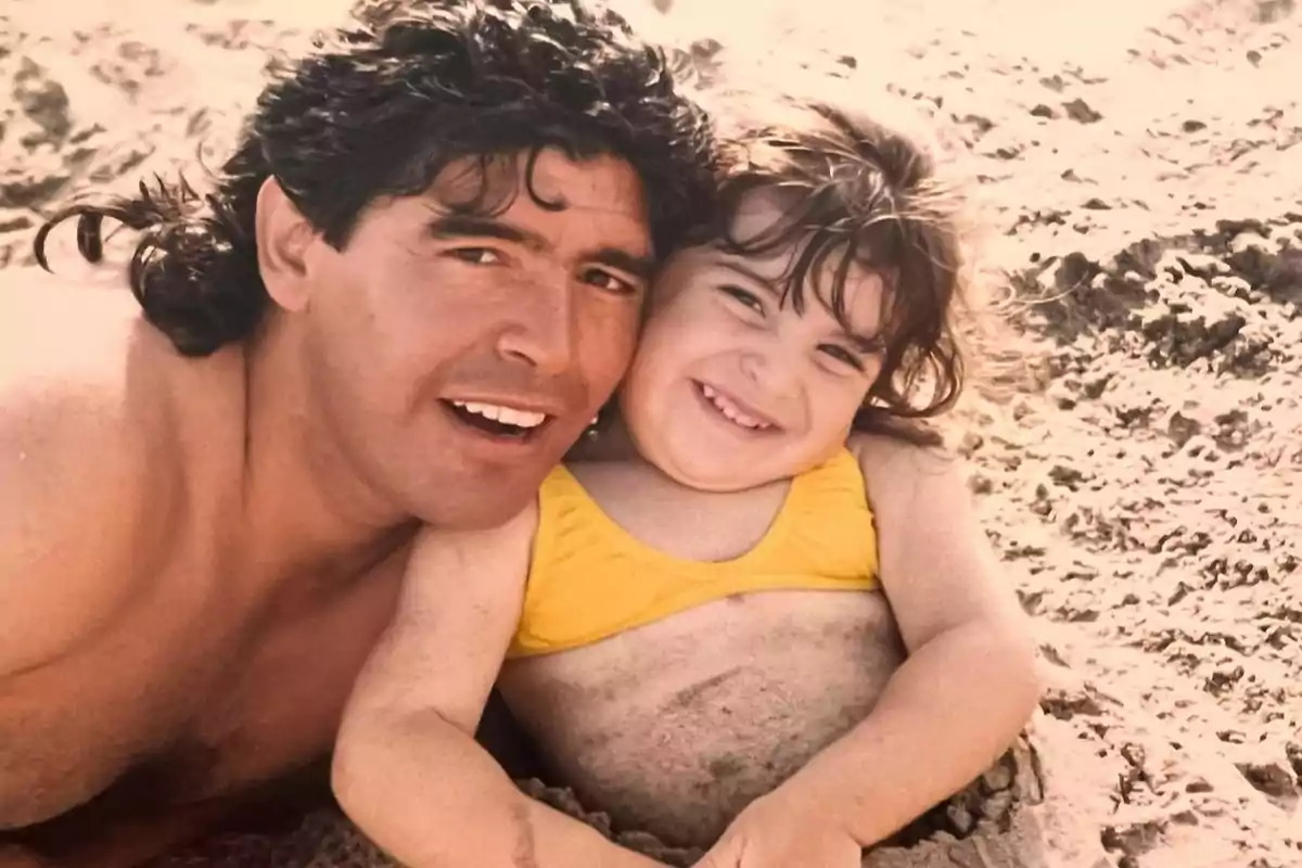 Hombre y niña sonríen juntos en la playa mientras están sentados en la arena Hombre y niña sonríen juntos en la playa mientras están sentados en la arena