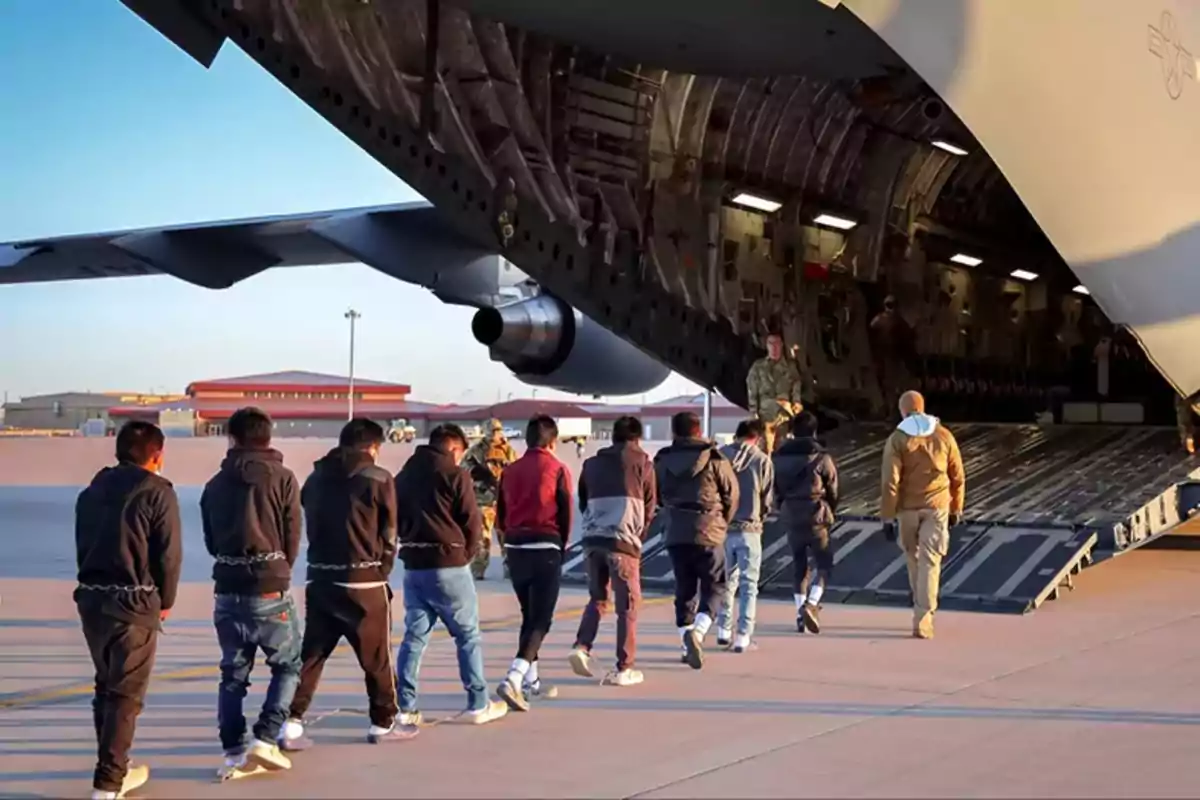 Un grupo de personas sube a un avión militar en una pista de aterrizaje.